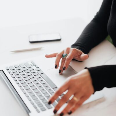 A businesswoman's hands typing on a laptop at a bright, modern workspace.